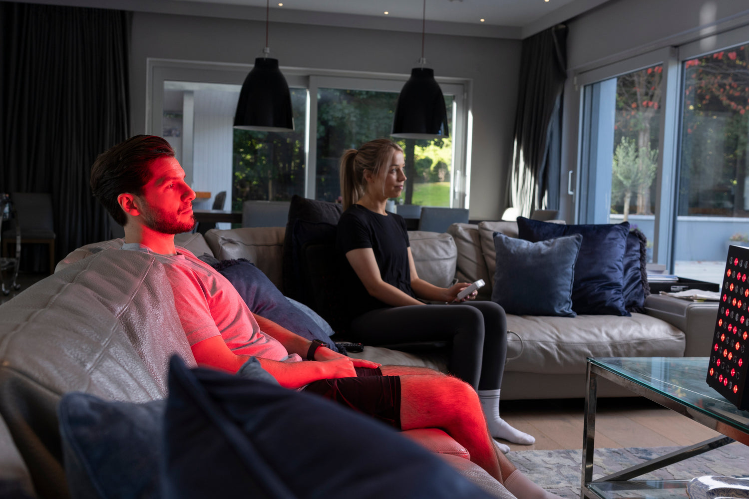 man sitting on couch at home and getting red light therapy